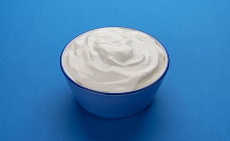 Bowl of sour cream on blue backgroundの写真素材