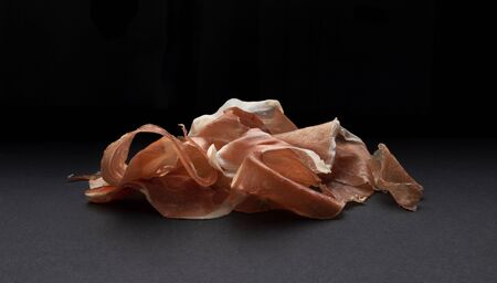 Heap of jamon slices, raw pork ham on black background