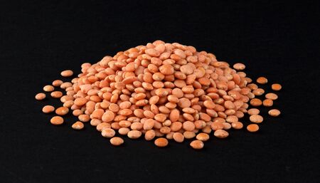 Heap of dry red lentils isolated on black background, closeup