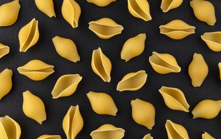 Conchiglie rigate. Dry shell pasta pattern on black background, top view, flat lay textureの写真素材