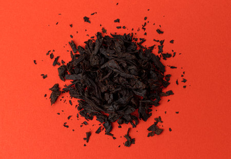 Pile of Dry tea leaves on red background, top view