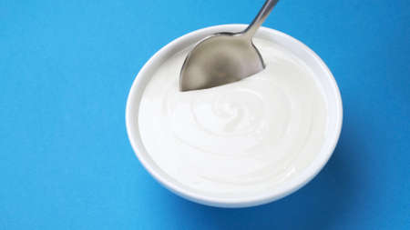 Bowl of sour cream, greek yogurt with spoonの写真素材