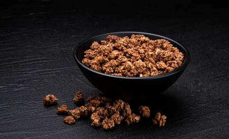 Chocolate granola on black background, bowl of crunchy muesliの写真素材
