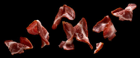 Falling sliced bacon isolated on black backgroundの写真素材