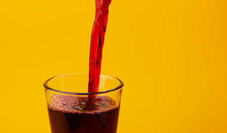 Pouring cherry juice isolated on yellow color background with copy spaceの写真素材