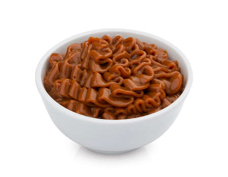 Boiled condensed milk, small bowl of melted caramel sauce isolated on white background