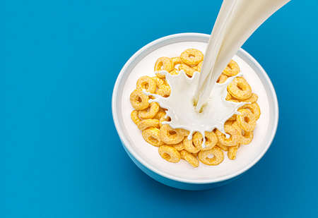 Corn rings with pouring milk on blue background, top viewの写真素材