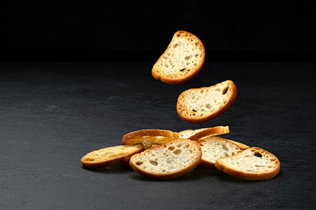 Falling bruschetta crackers, round bread croutons isolated on black background with copy space, full depth of fieldの写真素材