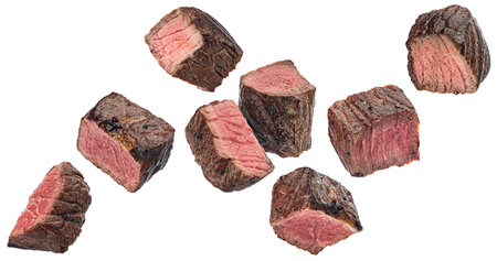 Medium rare steak pieces, sliced grilled beef cubes isolated on white backgroundの写真素材