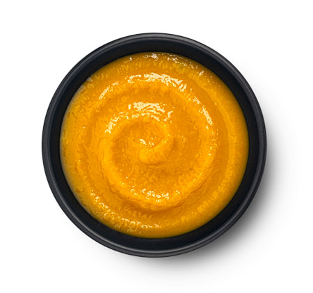 Pumpkin cream soup in black bowl isolated on white backgroundの写真素材