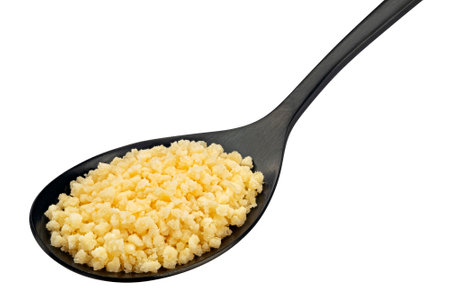 Grated parmesan cheese in black spoon isolated on white backgroundの写真素材
