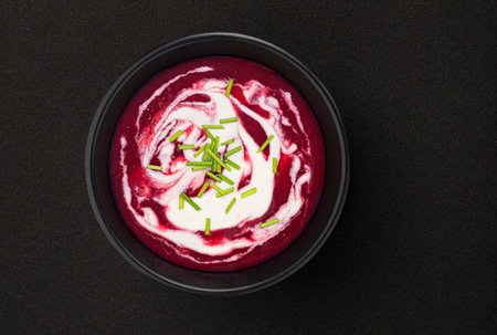 Beetroot soup with sour cream in black bowl on black background with copy space, top viewの写真素材