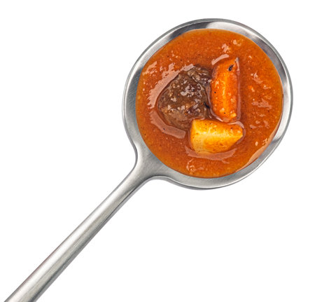 Beef stew with carrot and potato in spoon isolated on white background, top viewの写真素材