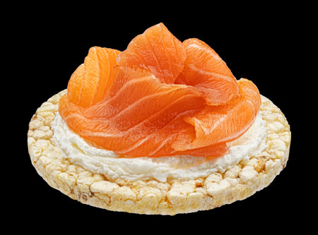 Puffed rice cake with smoked salmon slices and cream cheese isolated on black backgroundの写真素材