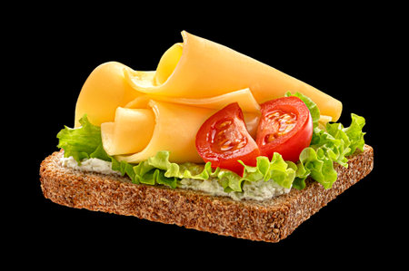 Cheese sandwich with lettuce and tomato on bread isolated on black backgroundの写真素材