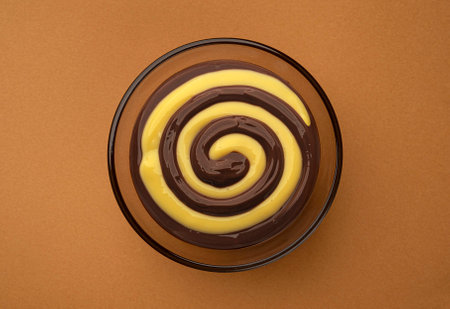 Bowl of chocolate and cream swirl on brown background, top viewの写真素材