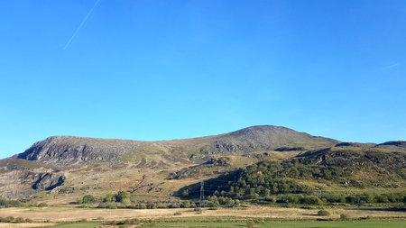 Mountain landscape with green fields and blue sky in Scotland, UKの写真素材