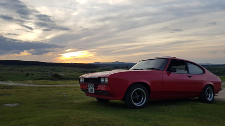 Sunset over a red car on the top of a hill.の写真素材