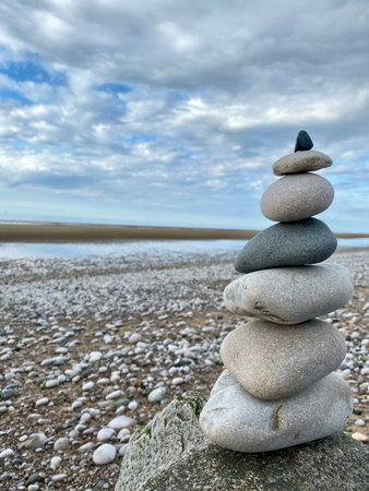 Pyramid of pebbles on the beach with blue sky and cloudsの写真素材