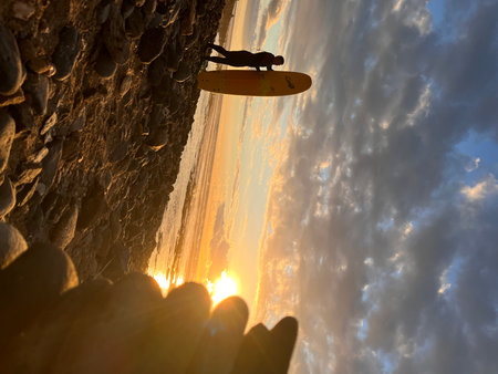 Silhouette of a surfer on a board against the sunsetの写真素材