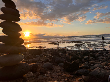 Sunset at the beach with a pyramid of pebble stonesの写真素材