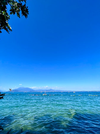 Tropical beach with clear blue water and mountains in background.の写真素材