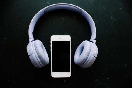 Smartphone and headphones on the blackboard background. Music concept.