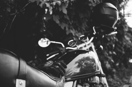 A close-up of a classic motorcycle's gas tank and leather seat, with a helmet resting on the...