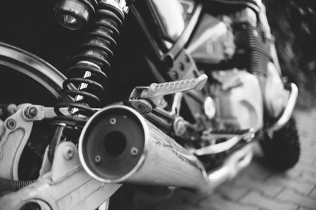 A monochrome image capturing a close-up of a vintage motorcycle. Details include the textured leather seat, chrome accents, and mechanical components.の写真素材