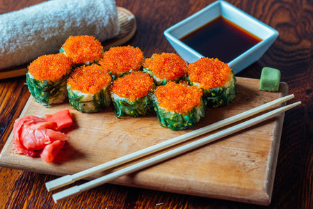 A plate of sushi with chopsticks and a bowl of sauce. The sushi is garnished with red and green ingredientsの写真素材