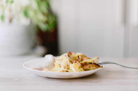 A plate of food with a fork on it. The food is potatoes and it is on a white plateの写真素材