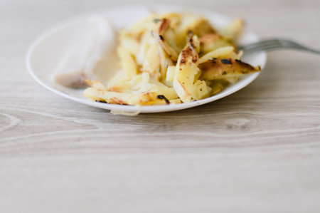 A plate of food with a fork on it. The plate has a piece of meat and some potatoesの写真素材