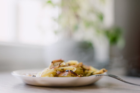 A plate of food with a fork on it. The food is potatoes and it is on a white plateの写真素材