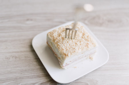 A fork is on a plate with a piece of cake. The fork is silverの写真素材