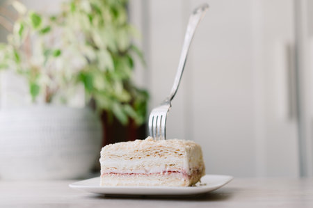 A fork is being used to eat a piece of cake. The cake is on a plateの写真素材