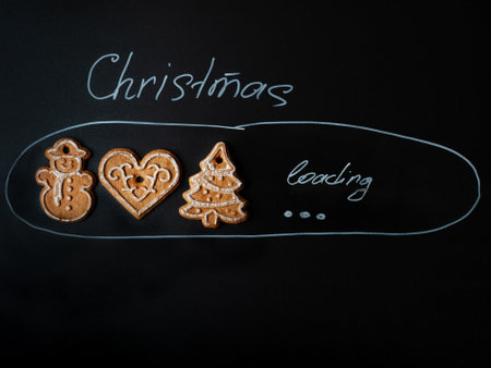 A blackboard with three cookies and a tree on it with the words Christmas Loading written above themの写真素材