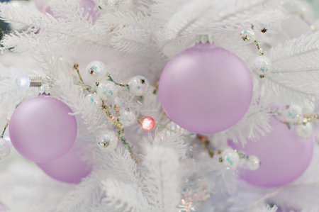 A white Christmas tree with a pink ball on it. There are several other balls on the treeの写真素材