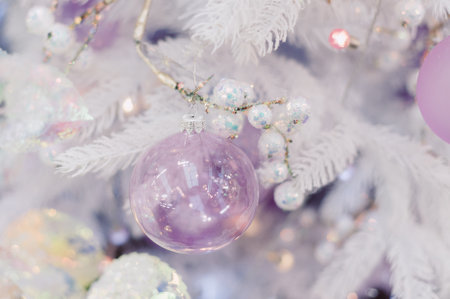 A white Christmas tree with a pink ball on it. There are several other balls on the treeの写真素材