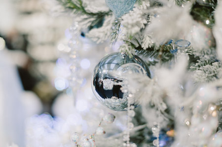 A tree with a silver ball on it. The ball is surrounded by snow. There are other balls on the tree as wellの写真素材