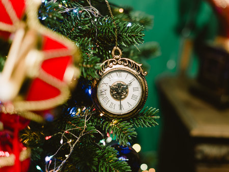 A gold and white clock hanging from a green background. The clock has Roman numerals on itの写真素材