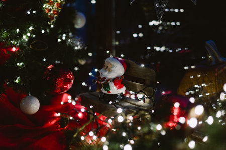 A christmas tree with a santa sitting on a bench. The bench is surrounded by lightsの写真素材