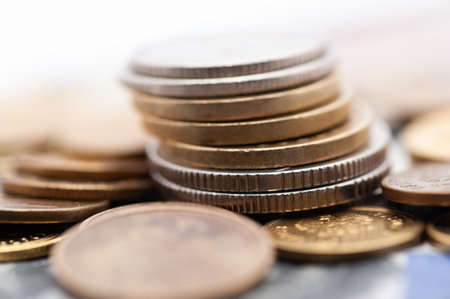 A stack of coins with a silver coin on top. The coins are of different sizes and colors