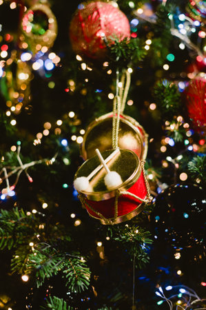 A gold and red Christmas ornament with a drum on it. There are also two gold and red ballsの写真素材