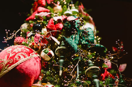 A red ball ornament hangs on a Christmas tree. The tree is decorated with many other ornamentsの写真素材