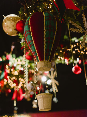 A Christmas tree with a balloon shaped ornament hanging from it. The ornament is a hot air balloon