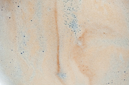 A white background with a brown swirl of foam. The foam is made up of bubbles. The bubbles are small and scattered throughout the foamの写真素材