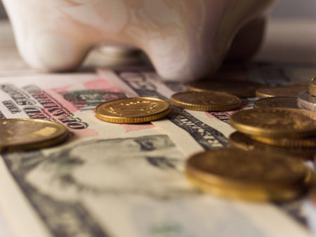 A pile of coins and a piggy bank. The coins are gold and silverの写真素材