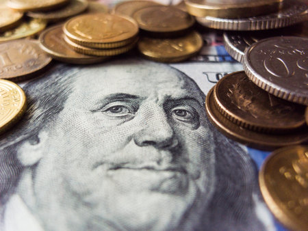 A stack of coins and a dollar bill. The coins are of different sizes and colors