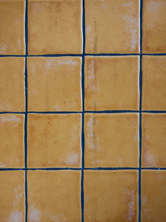 Bright yellow square tiles arranged in a grid pattern with white grout lines, creating a vivid, modern, and cheerful surface. High quality photoの写真素材
