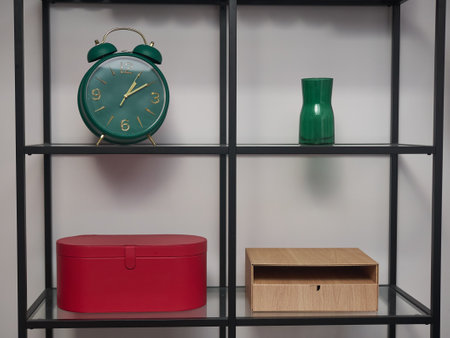 A green alarm clock sits on a shelf next to a red box and a green vase. The clock is set to the time of 10-30の写真素材
